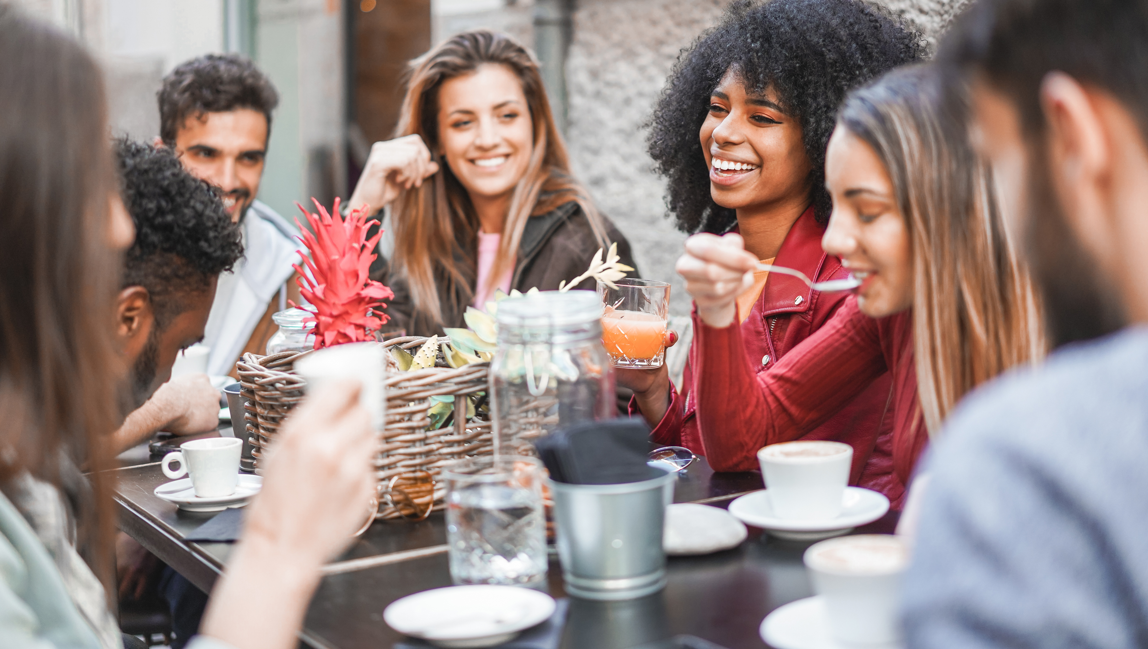 group of young adults enjoying meal together at outdoor table
